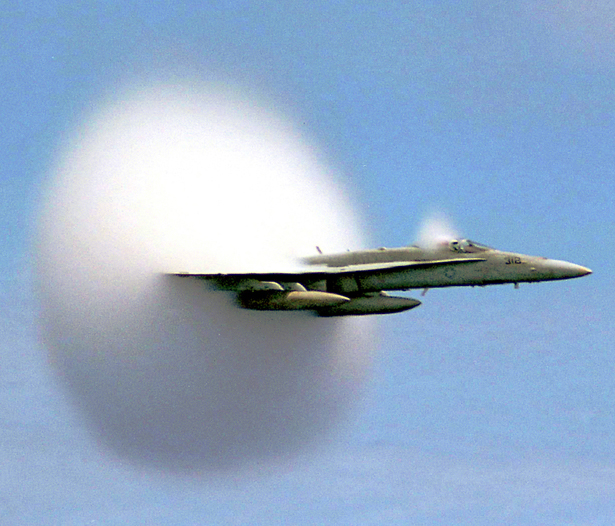 As a work of the U.S. federal government, this image is in the public domain. Rapid condensation of water vapor due to a sonic shock produced at sub-sonic speed creates a vapor cone (known as a Prandtl–Glauert singularity), which can be seen with the naked eye